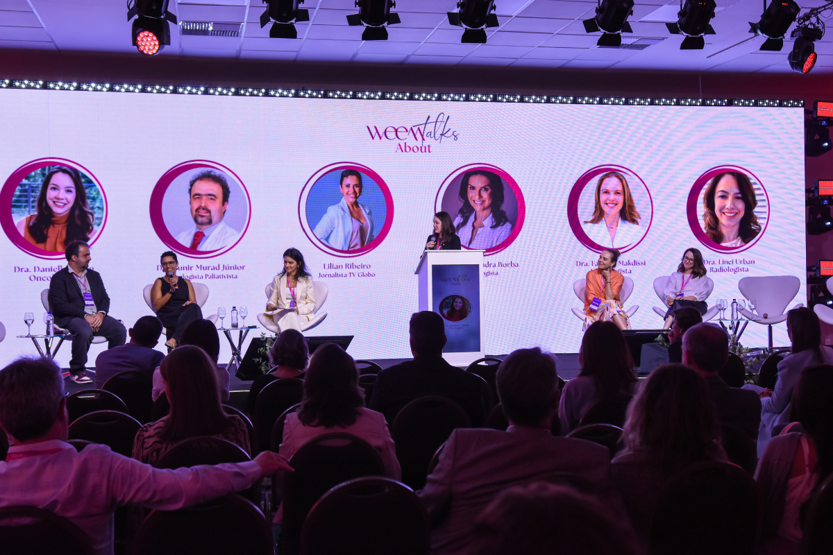 Palco weeTalks com seis especialistas no telão e quatro painelistas debatendo perante a plateia.