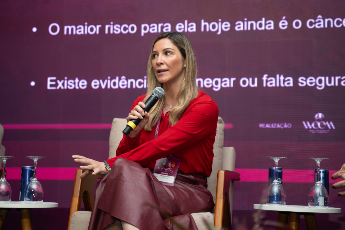 Participante de blusa vermelha fala ao microfone durante um painel do WEEM Talks 2026.