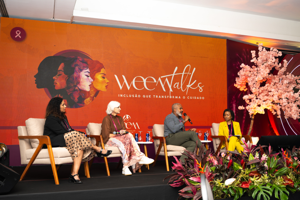 Quatro participantes sentados no palco durante um painel do WEEM Talks 2026, diante do cenário oficial do evento.