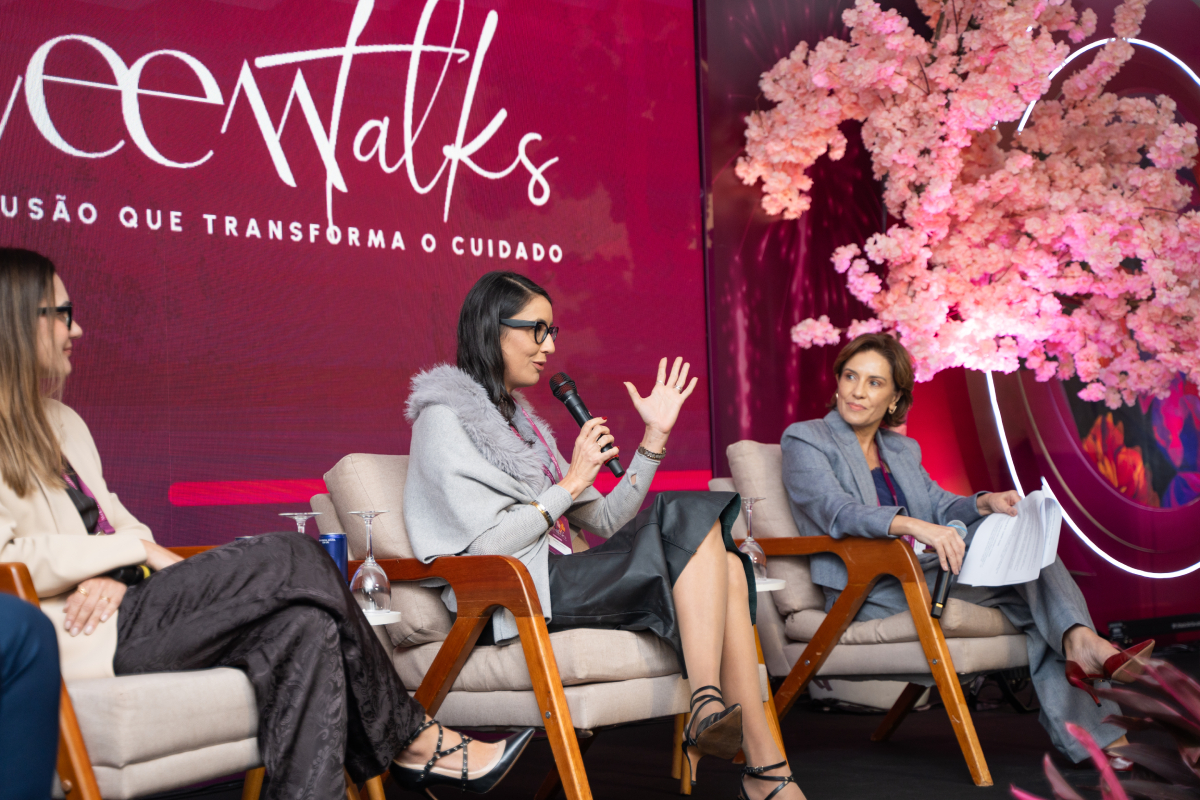 Participante fala ao microfone e gesticula durante discussão em painel no palco do WEEM Talks 2026.